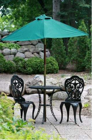Outdoor table and two chairs beneath a green patio umbrella