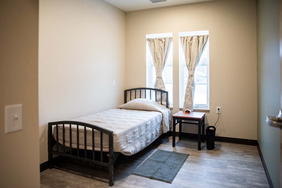 Simple bedroom with twin bed, nightstand, and two windows