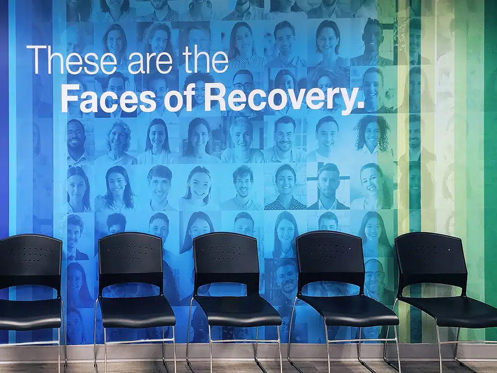 Chairs in front of colorful Faces of Recovery wall