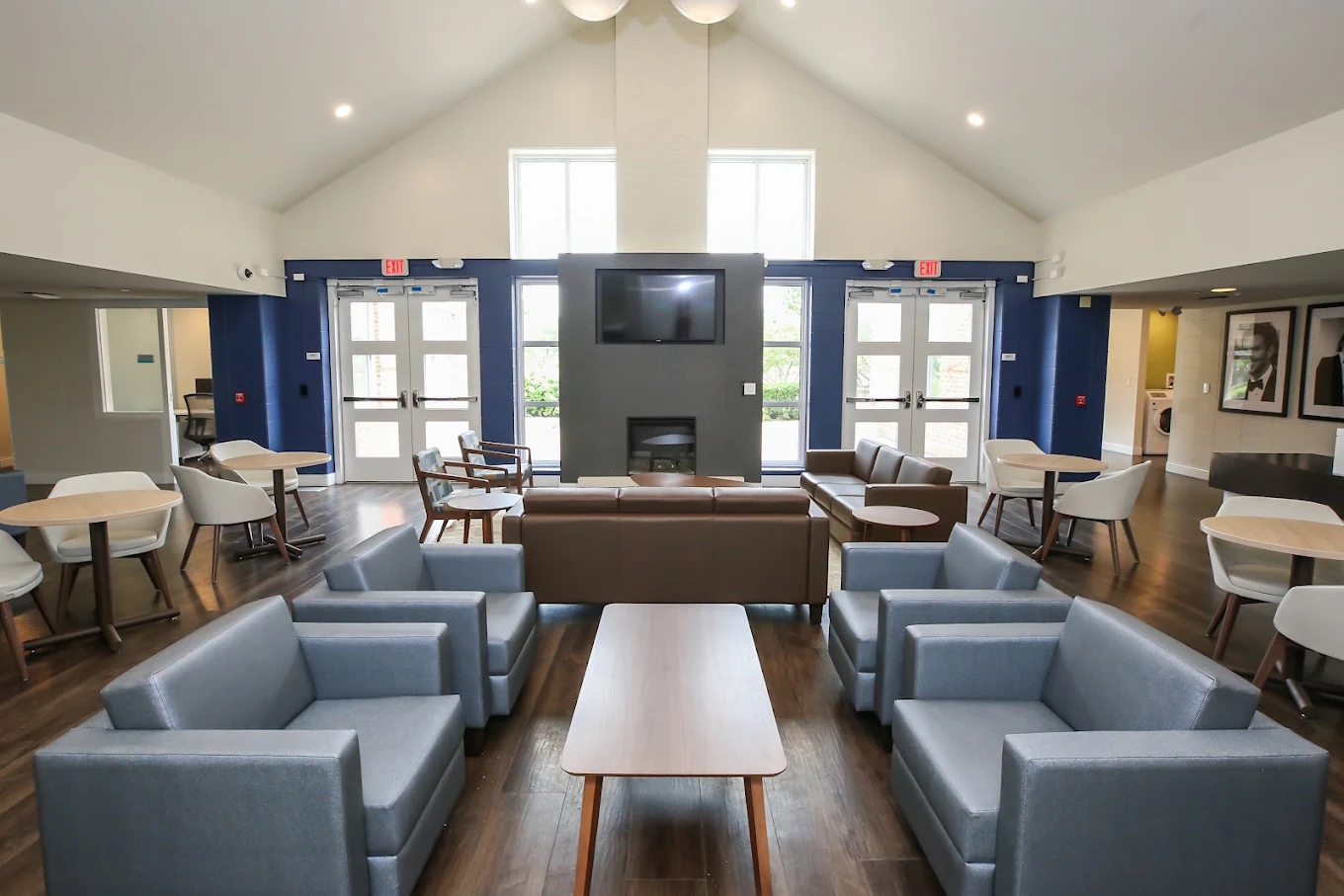 Spacious lounge with armchairs, tables, sofas, and television