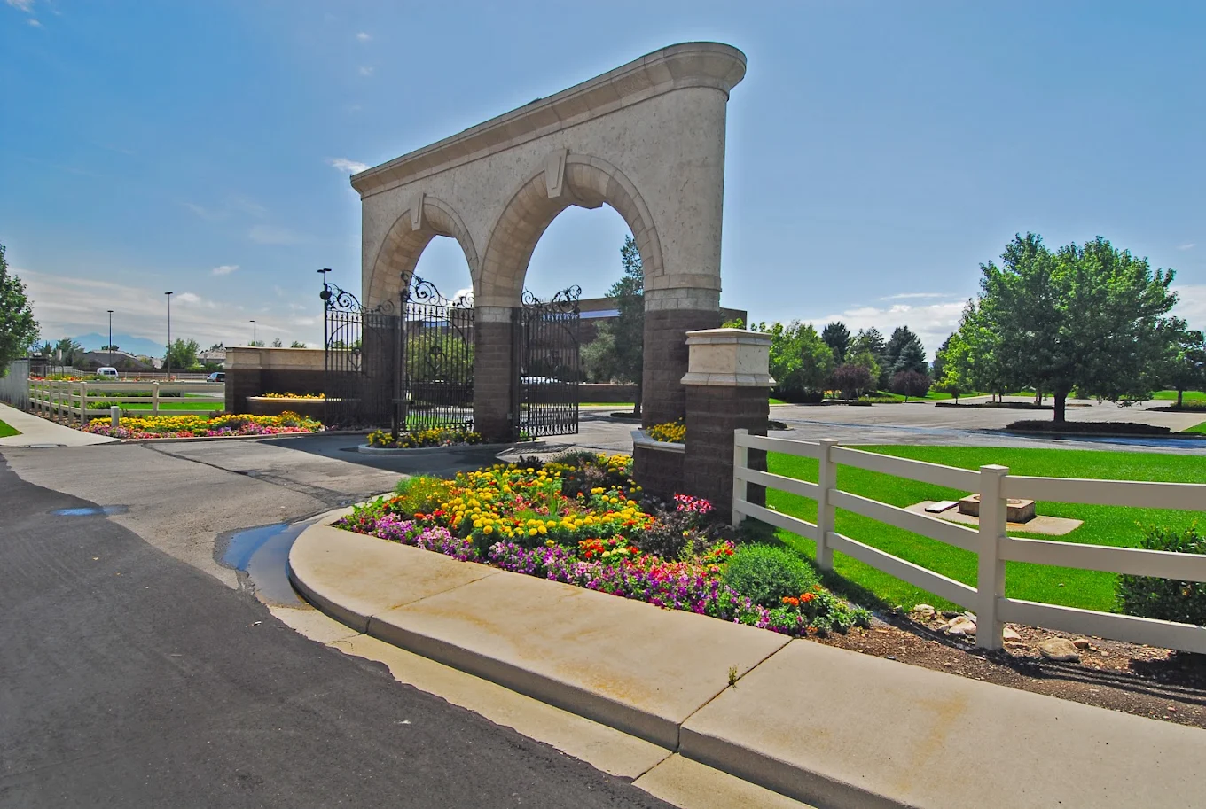 Stone arch entrance with flowers and green lawn under blue sky