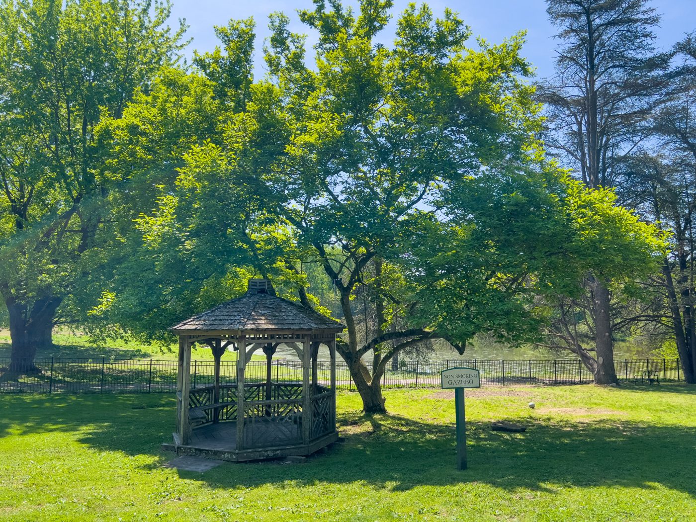 Wooden gazebo beside pond and trees on landscaped treatment center grounds