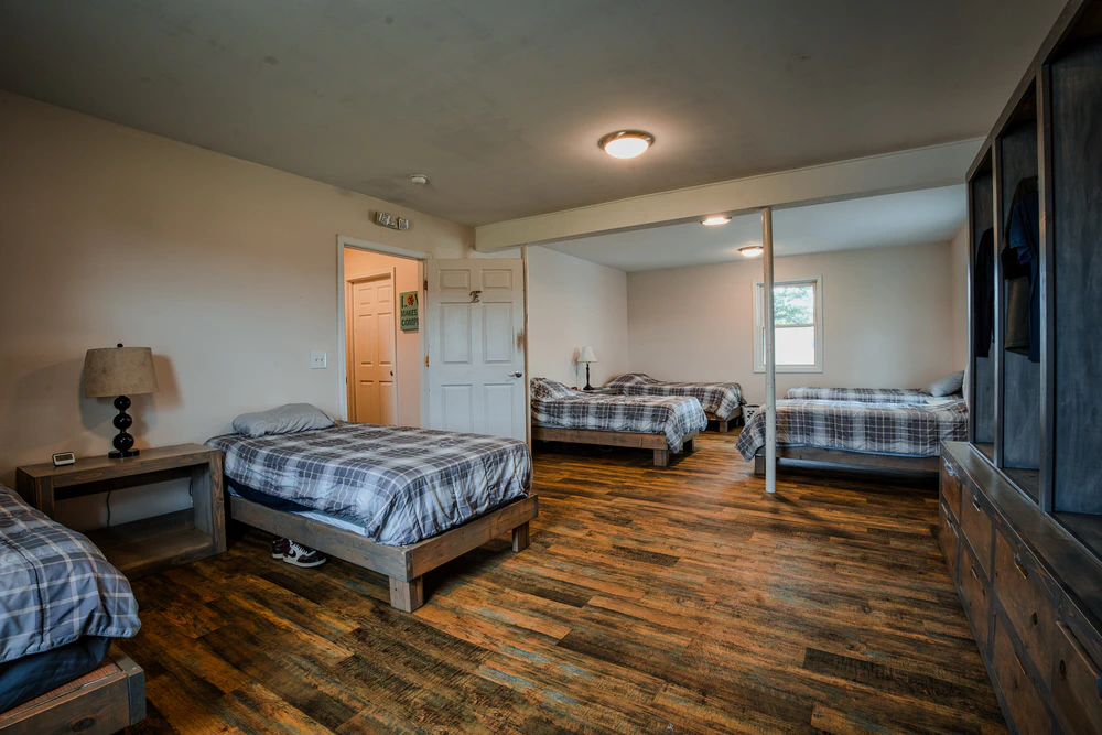 Shared bedroom with multiple beds and wooden flooring