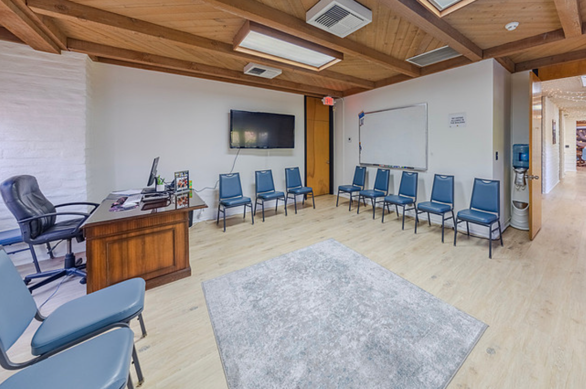 Therapy room with chairs in circle and desk with TV.