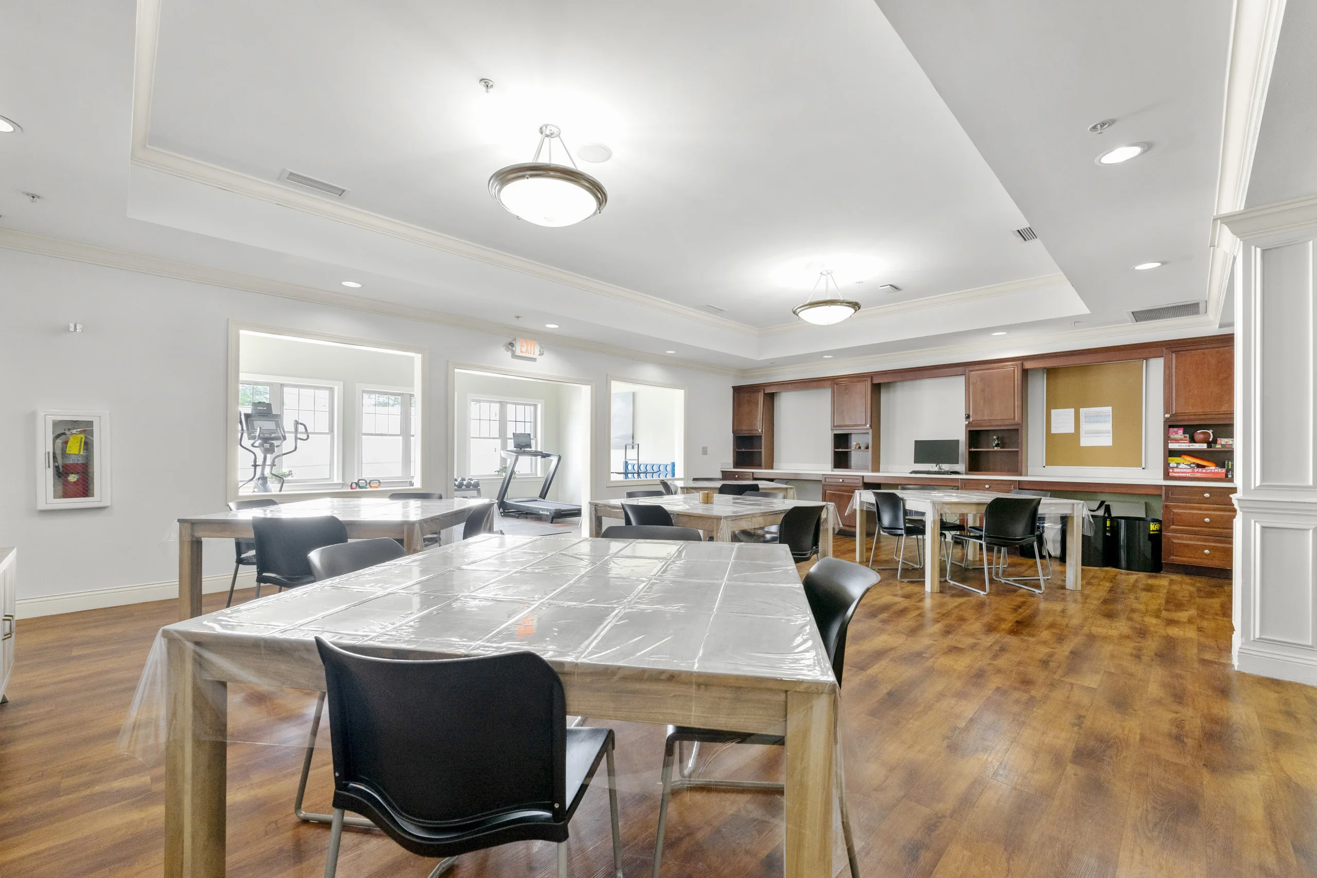 Multi-purpose activity room with tables, workspace, and access to the fitness center for therapeutic programming