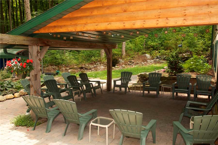A tranquil covered patio with Adirondack chairs in a forest setting