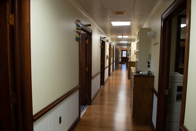 Long hallway with private rooms and handrails