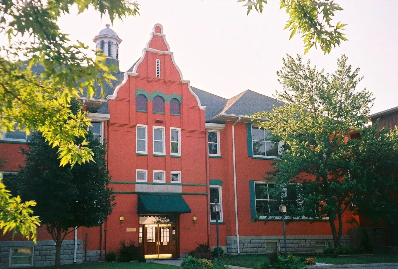 Red brick building with green trim and arched roofline